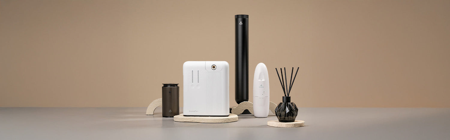 A set of four aroma diffusers with different shapes and sizes, displayed on beige stone-like stands. The background is a plain neutral beige color.